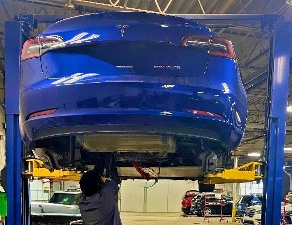 Axelrod-tech-under-Tesla-lift cleveland auto body shop tesla on lift